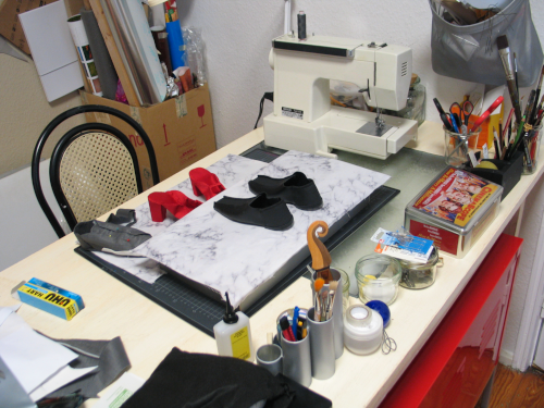 Arbeitstisch mit rotem Unterschrank und mit Objekt in Entstehung, Materialien und N�hmaschine im Hintergrund