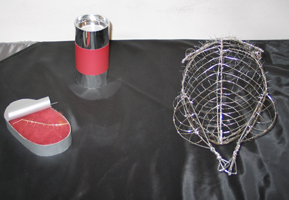 geöffnete 'Fischdose', 'Konservendose´ und aus Silberdraht geformtes Gerippe eines 'Hühnchens' auf schwarzem Tuch